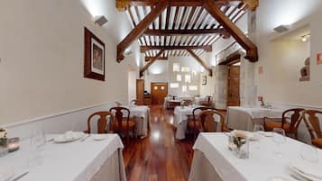 Un restaurante con vigas de madera, mesas y sillas blancas.