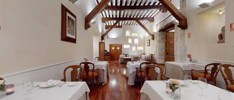 A restaurant with wooden beams, white tables, and chairs.