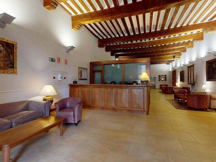 A lobby with a wooden reception desk, cushioned seating, and a tiled floor.