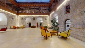 A spacious lobby with stone walls, wooden beams, and a high ceiling. There are several seating areas with chairs and tables. - AZZ Peñafiel Las Claras Hotel & Spa (Penafiel)