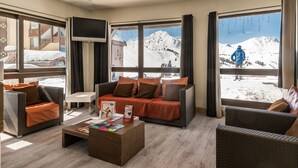 Una habitación de hotel moderna con un gran ventanal que ofrece vistas a una montaña nevada.