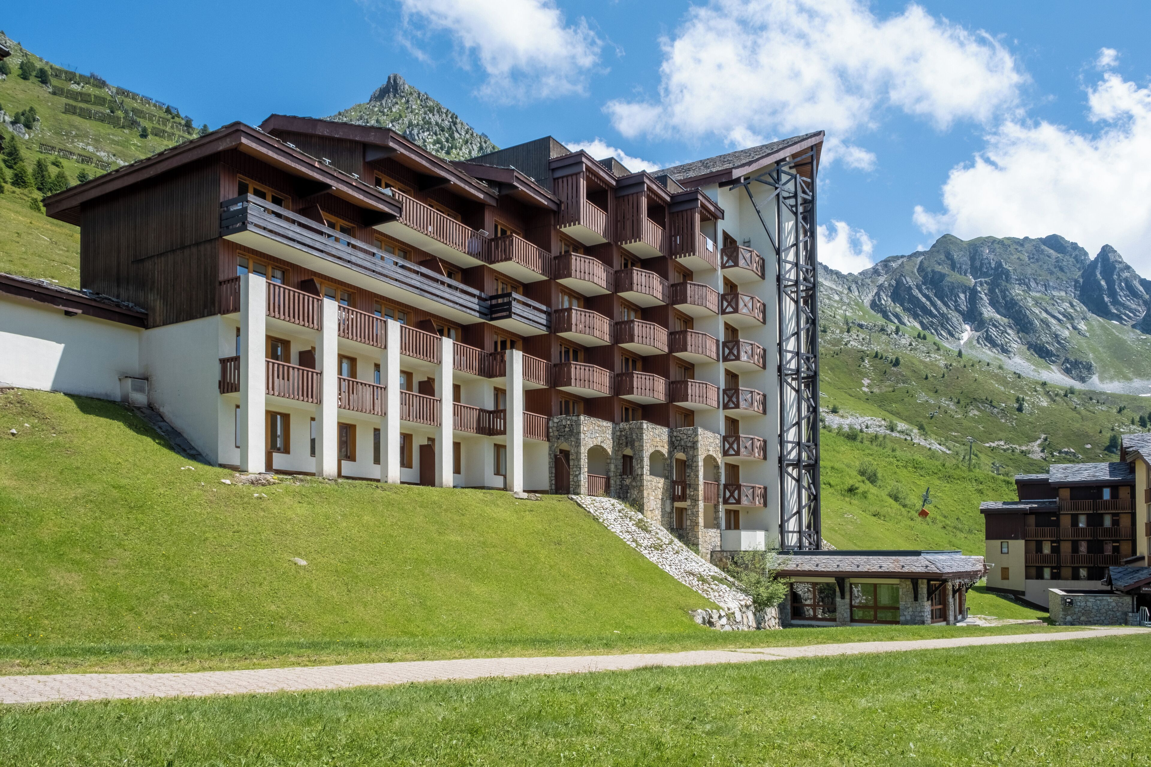 Un hôtel à plusieurs étages, doté de balcons, situé dans un cadre montagneux.