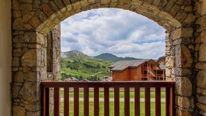 Un arco de piedra que conduce a un balcón con vistas a un paisaje montañoso y un edificio de madera.