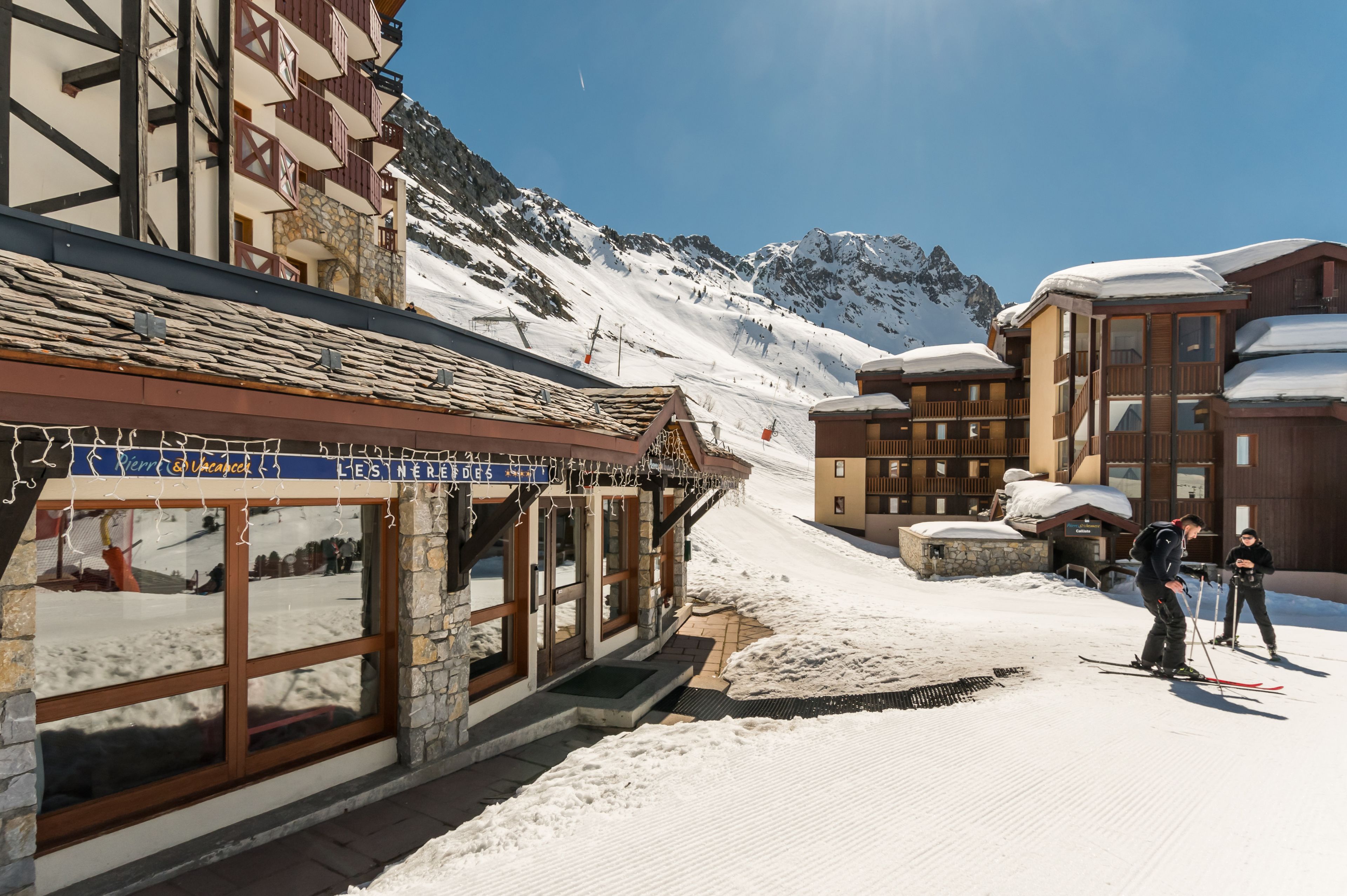 A ski resort building with a stone facade, large windows, and a sign indicating it's a ski lodge.