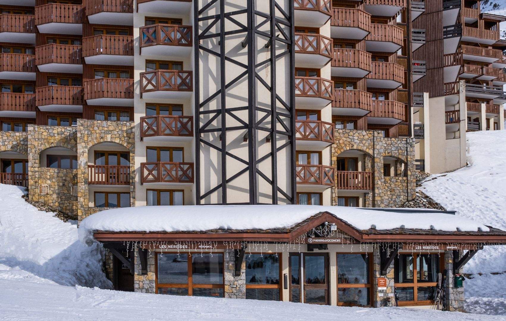 A multi-story hotel with stone and timber framing, balconies, and a snow-covered entrance.