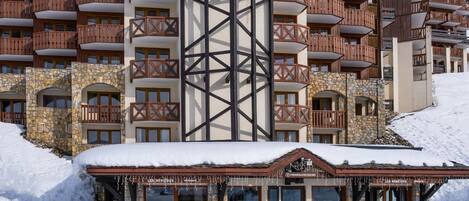 A multi-story hotel with stone and timber framing, balconies, and a snow-covered entrance.