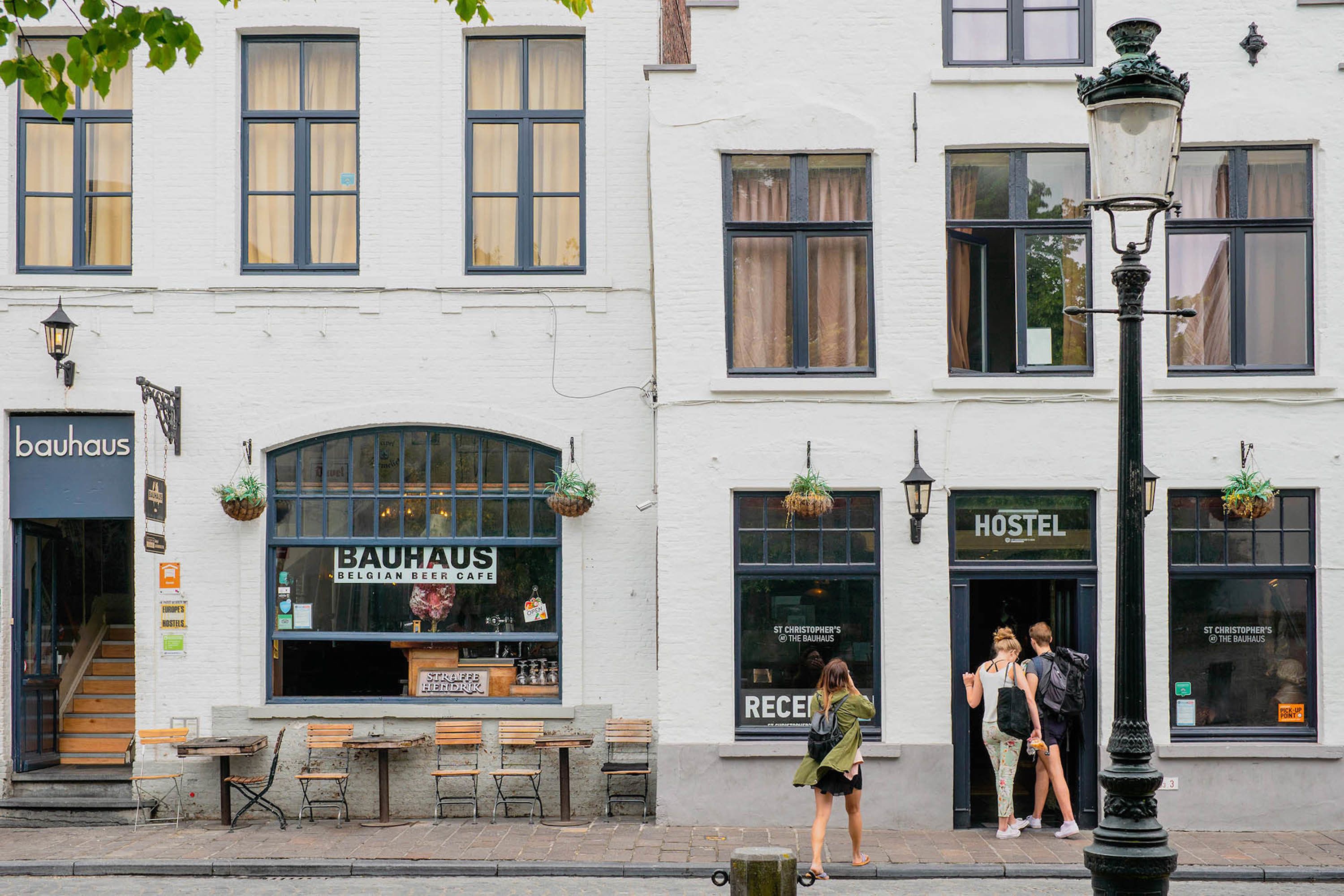 A building with a 'BAUHAUS' sign, a 'HOSTEL' sign, and outdoor seating with benches.