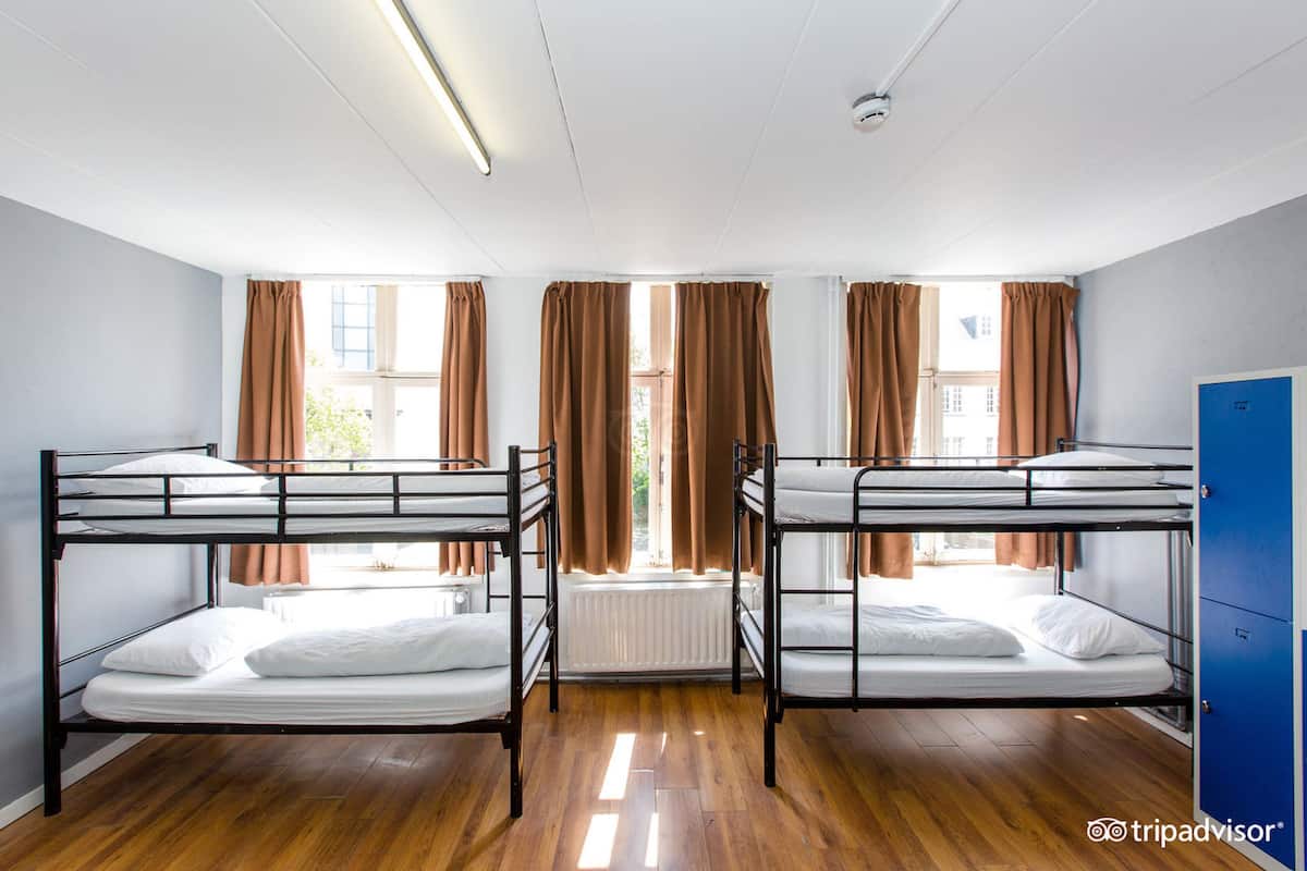 Een slaapzaal met stapelbedden, een radiator en een blauwe kast.