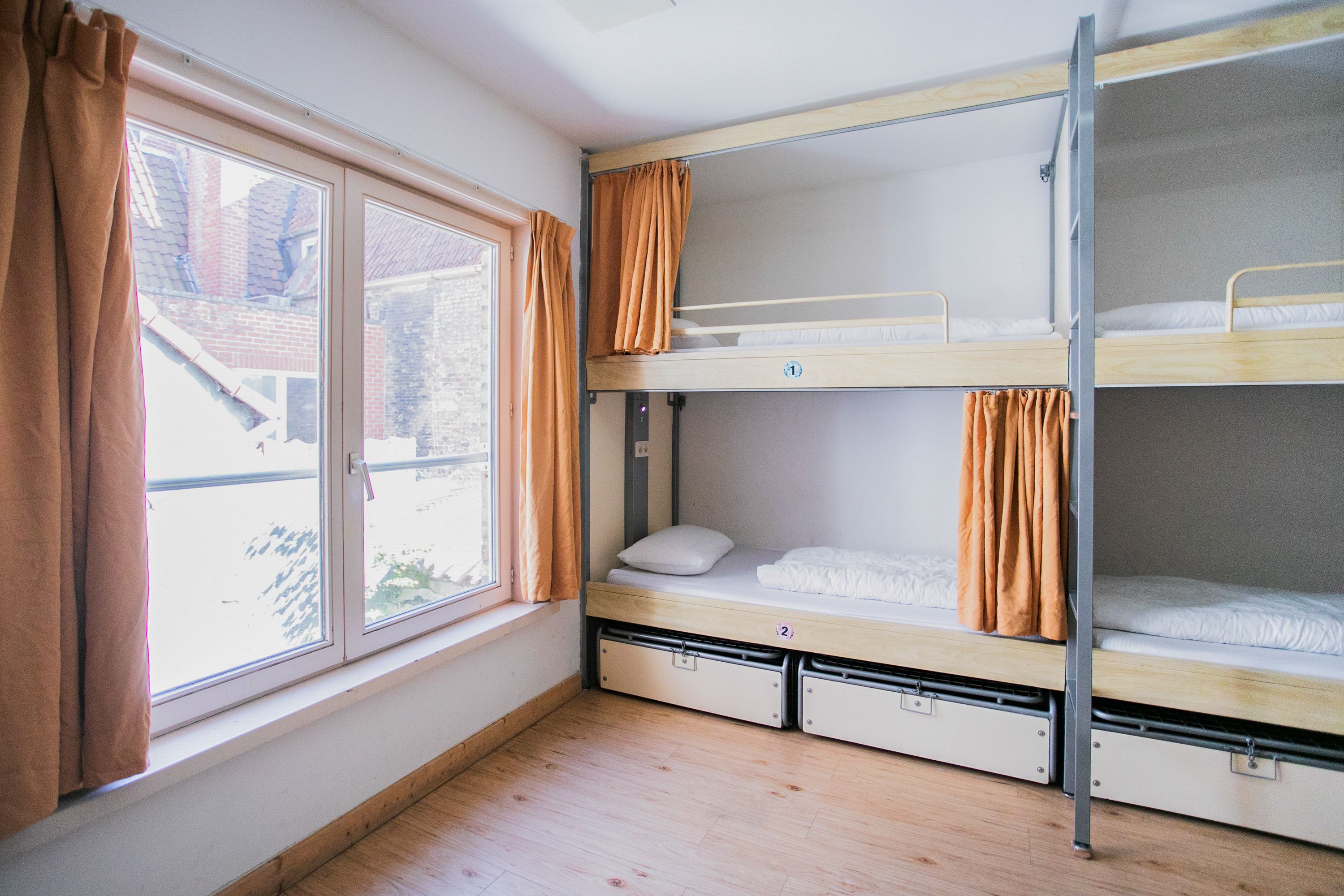 Un dormitorio con literas, una ventana con cortinas y vistas al exterior.