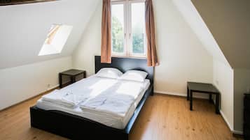 Une chambre à coucher avec un lit, une fenêtre avec des rideaux, une petite table et une table de chevet.