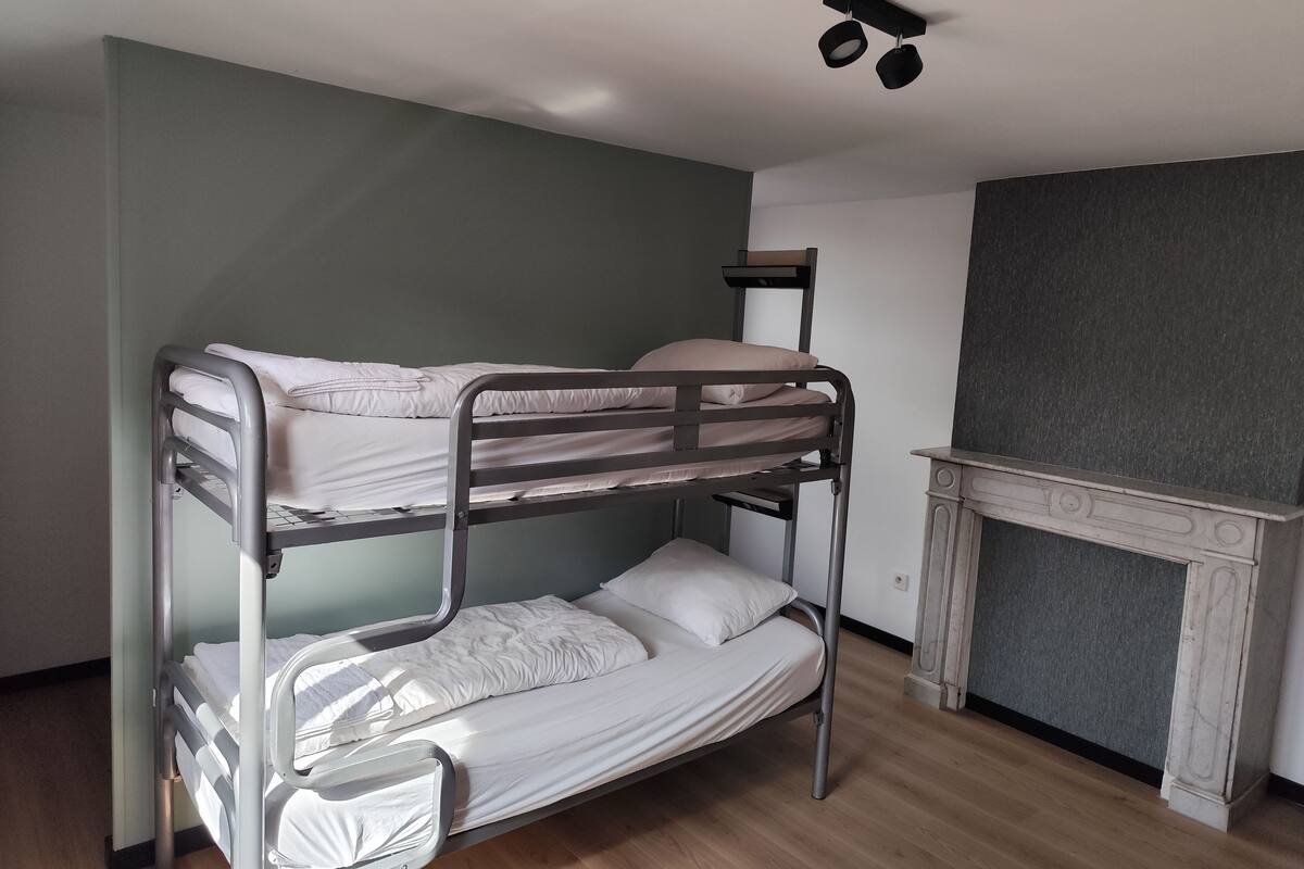 Een slaapkamer met stapelbed, open haard en raam.