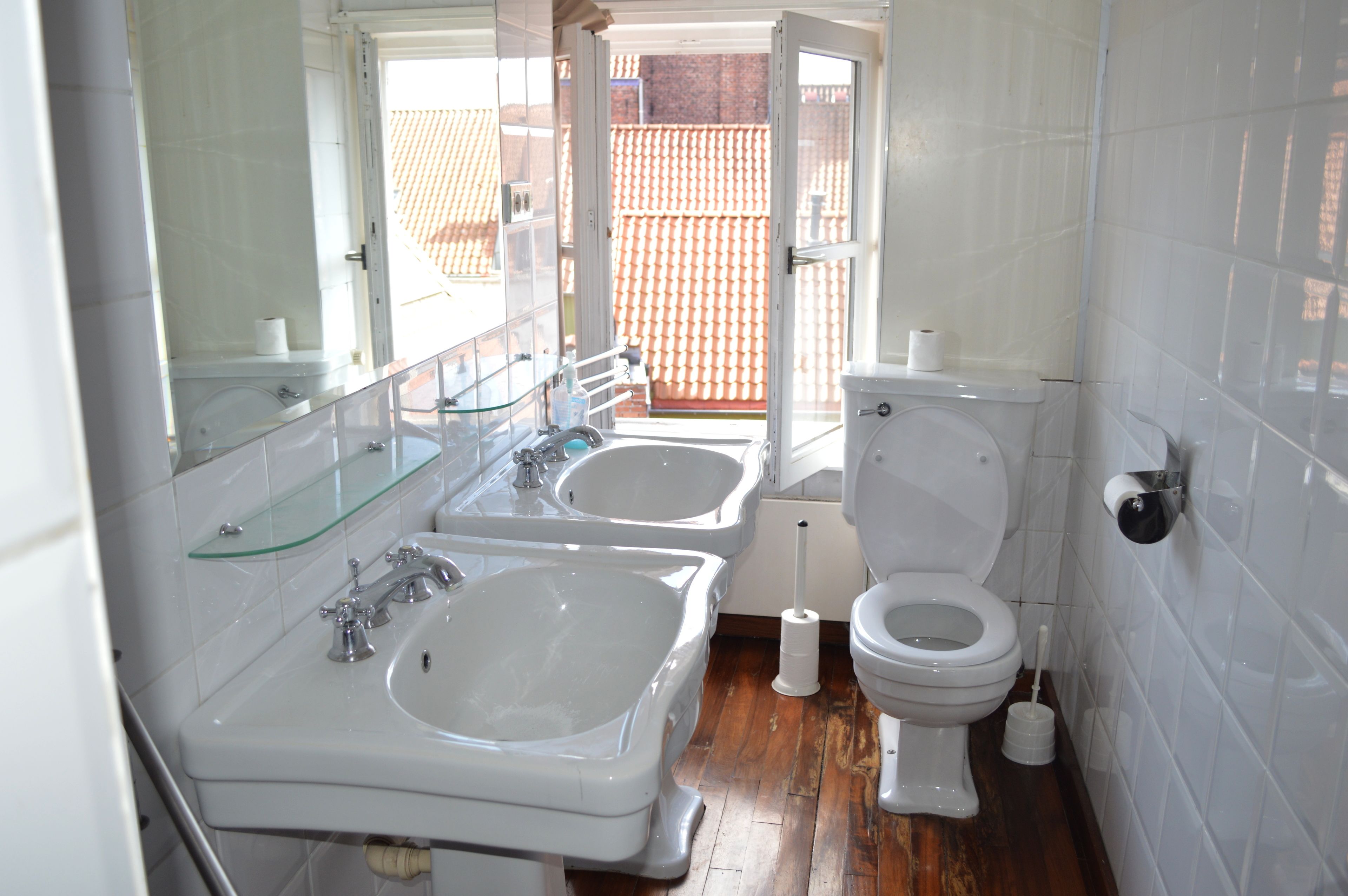 A bathroom with two sinks, a toilet, and a glass shower enclosure.