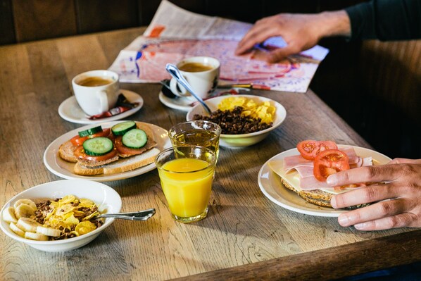 Desayuno con diversas opciones de comida y bebidas sobre una mesa de madera.