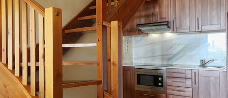 A kitchen with wooden cabinets, a stainless steel oven, and a marble countertop.