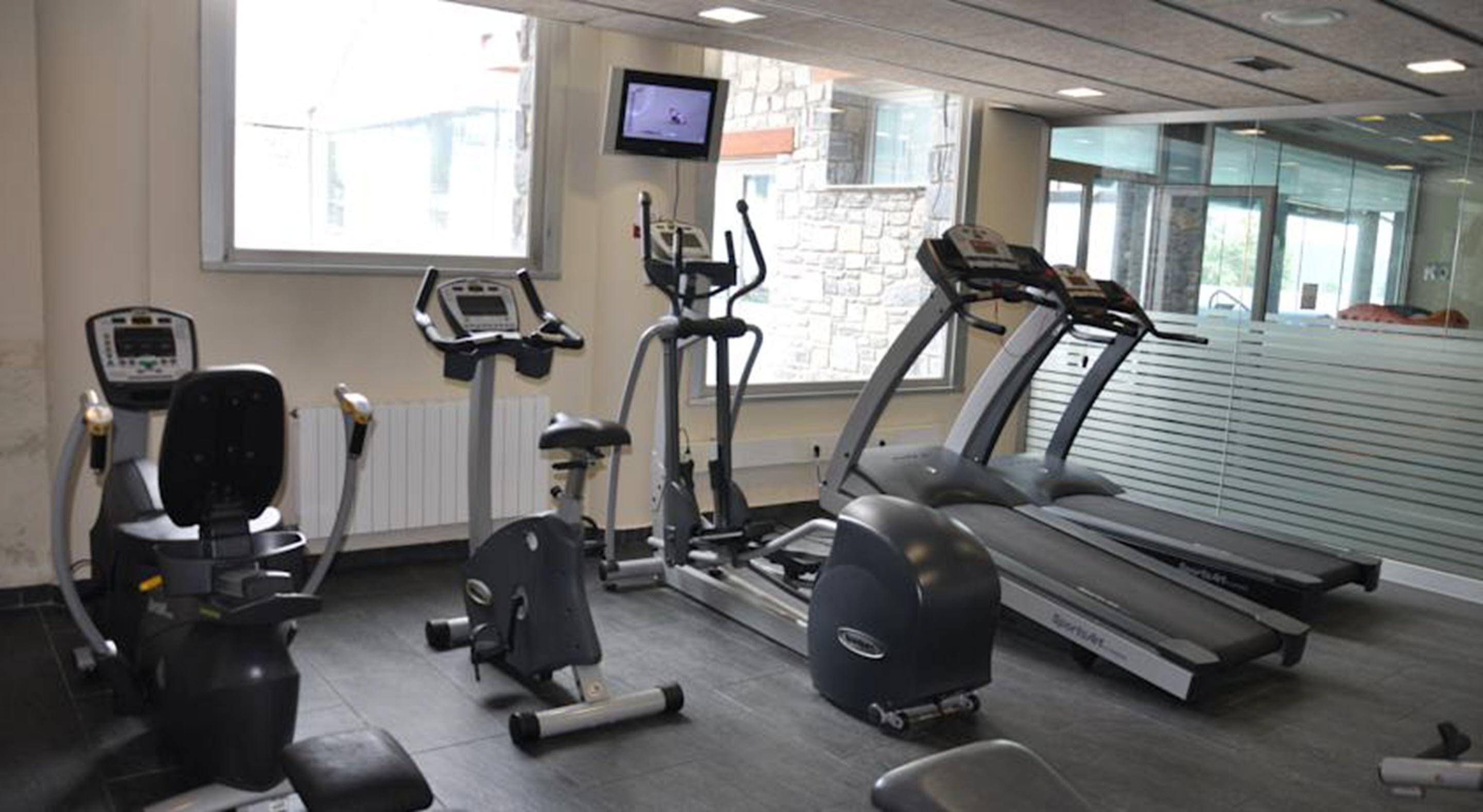 Un gimnasio con cintas de correr, elípticas y equipo de pesas.