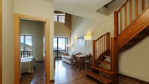 Un amplio salón con una escalera de madera, una mesa de comedor con sillas y un sofá.