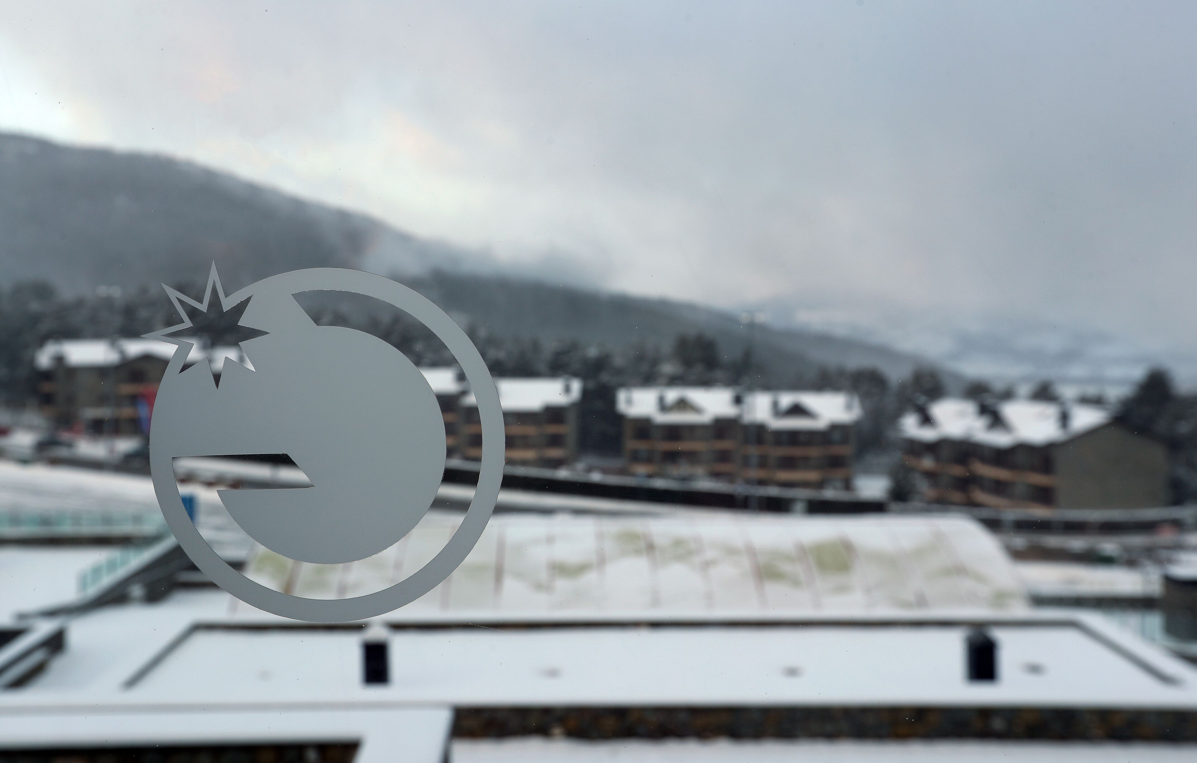 A hotel with a snow-covered roof and a mountainous backdrop.