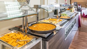 Un bufé con diversos alimentos, incluyendo aperitivos fritos y una gran bandeja de arroz.