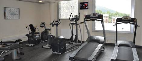 A gym with treadmills, elliptical machines, and a bench.