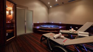 Zona de spa con hidromasaje, suelo de madera y dos sillones de descanso con toallas.