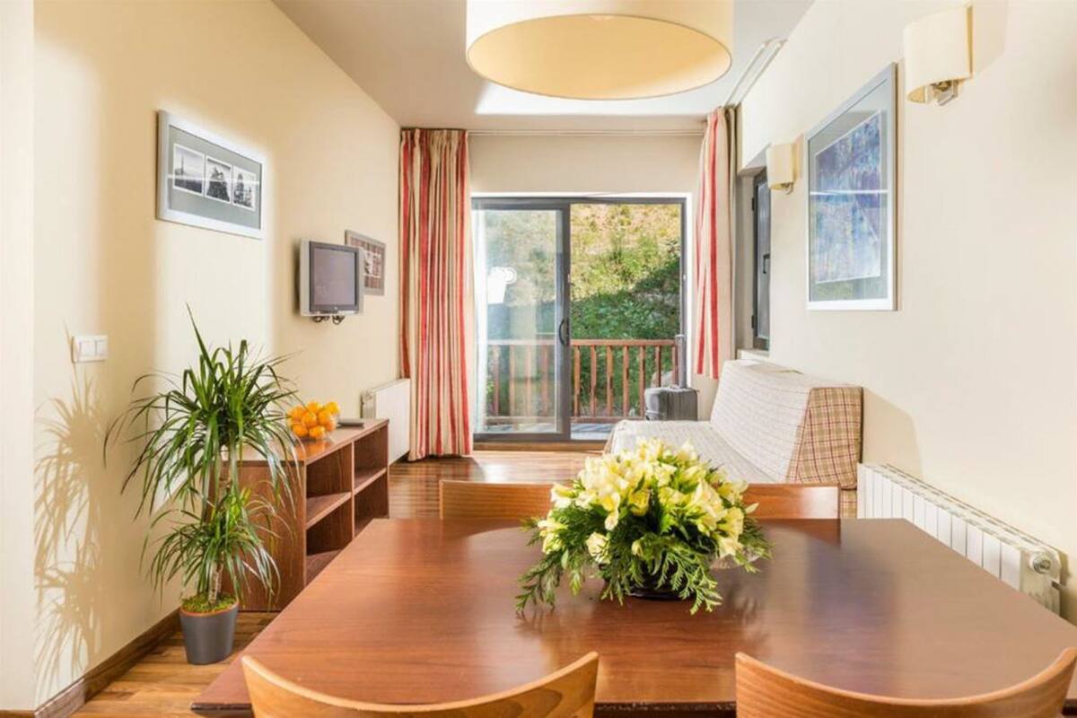 Un coin repas avec une table en bois, des chaises, une plante en pot et un bouquet de fleurs.