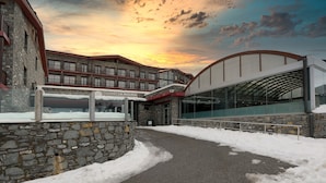 Entrada de un hotel con fachada de piedra y edificio de cristal.