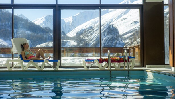 Zona de piscina con vistas a montañas nevadas a través de amplios ventanales.