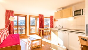 Una habitación acogedora con una cama, una mesa de comedor y una zona de cocina con microondas y fregadero.