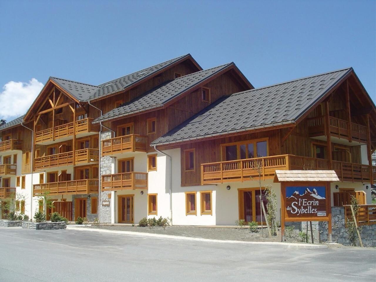 Un bâtiment en bois à plusieurs étages, doté de balcons, d’une enseigne indiquant « L’Ecrin des Sybbles » et d’une base en pierre.