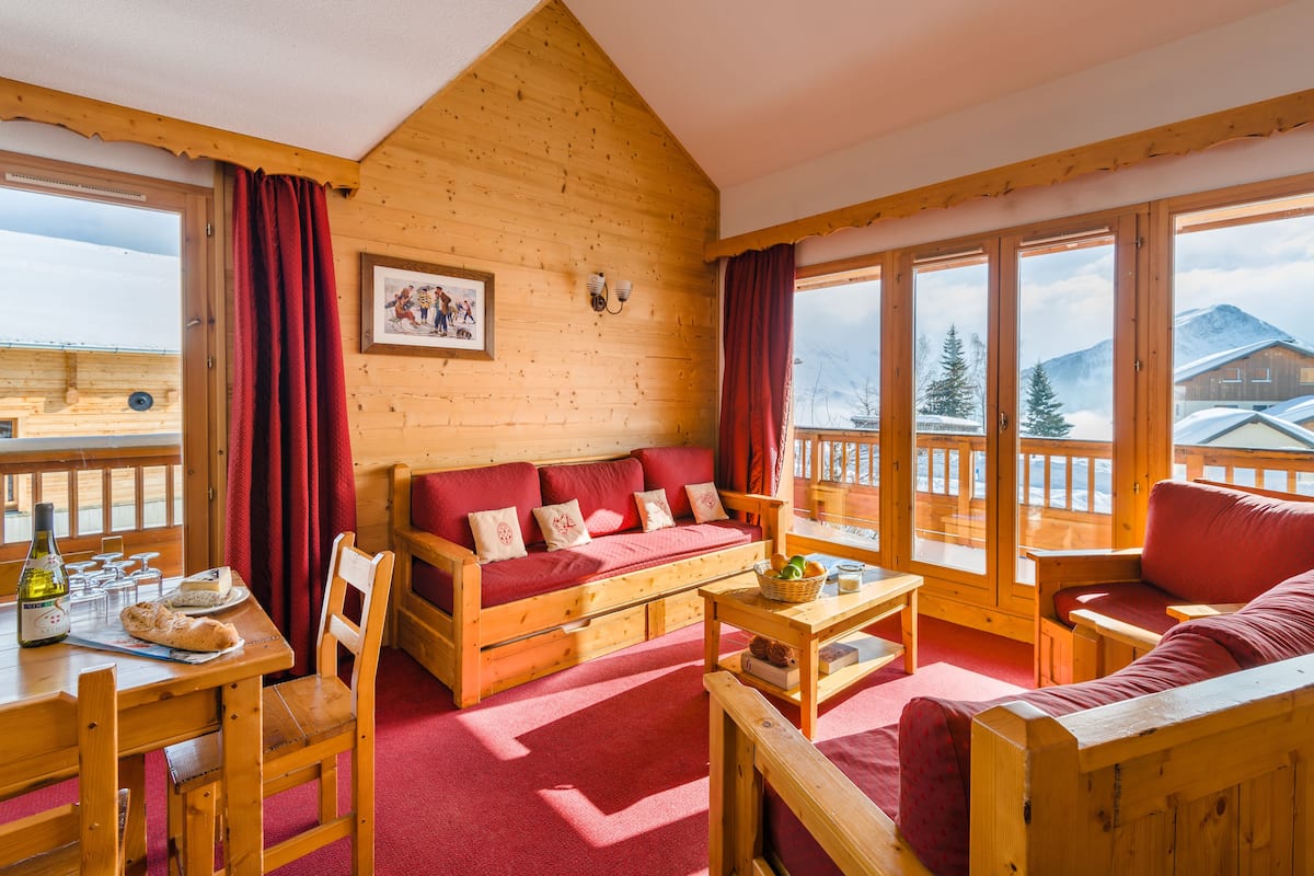Ein Holzblockhaus-Interieur mit einer Couch, einem Esstisch und Stühlen.