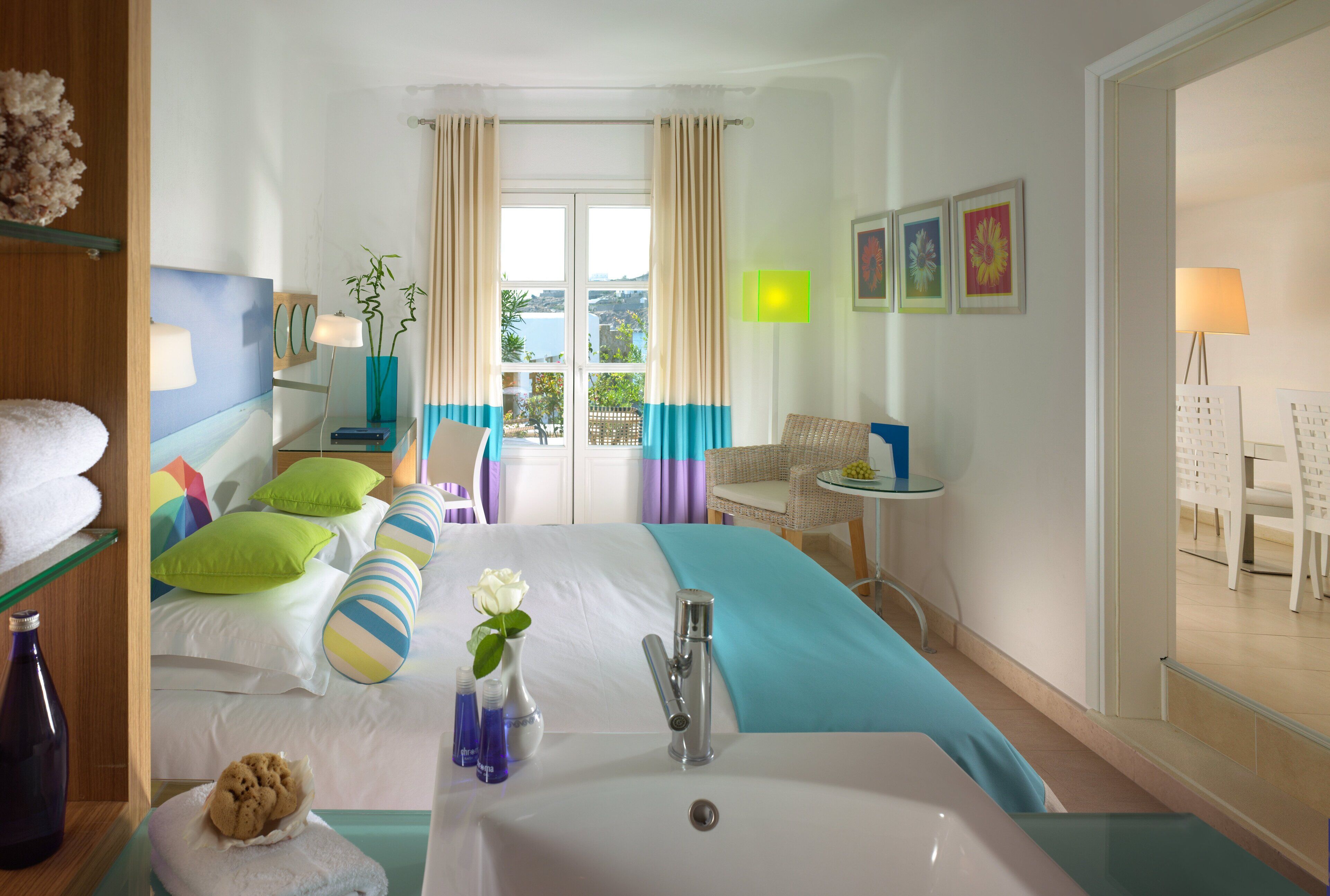 A hotel room with a large bed, a bathroom with a sink, and a view of the outdoors.