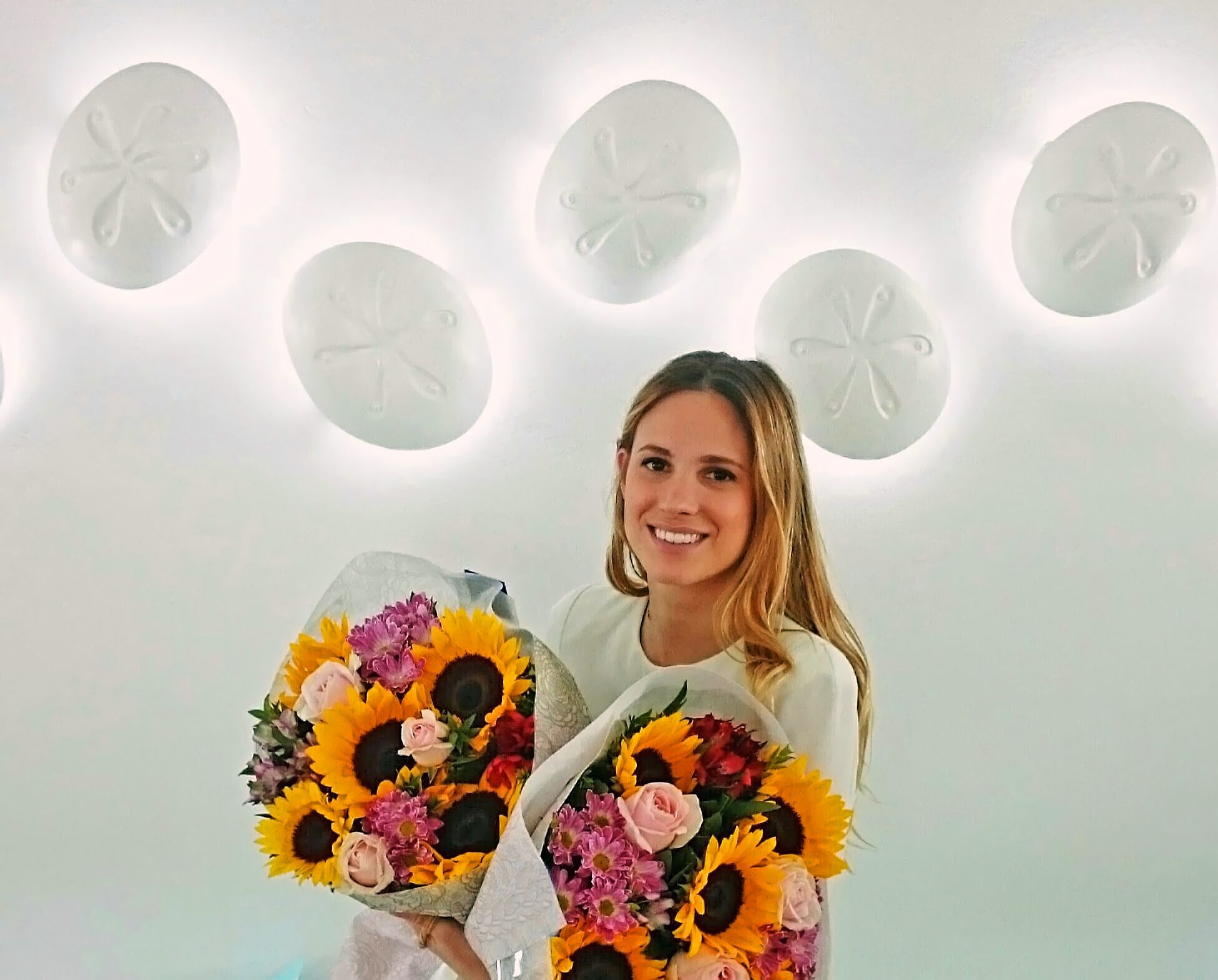 Uma pessoa segurando dois buquês de girassóis e rosas.