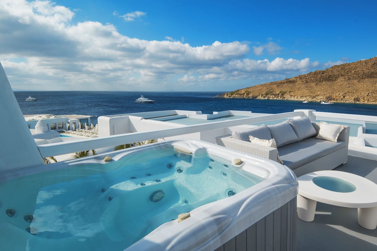 A hot tub and seating area with a view of the sea and boats.