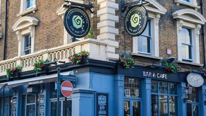 A building with a "BAR & CAFE" sign, a "No Entry" sign, and a "Badass Burgers" sign. - St Christopher's Inn, Greenwich - Hostel (London)