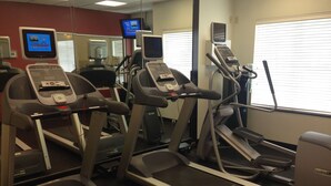 A gym with treadmills, stationary bikes, and a mirrored wall.