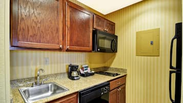 A kitchen with wooden cabinets, a stainless steel sink, a microwave, a coffee maker, and a dishwasher.