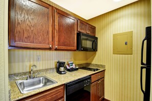 A kitchen with wooden cabinets, a stainless steel sink, a microwave, a coffee maker, and a dishwasher.