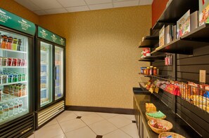 Een hotel kitchenette met een koelkast vol drankjes, een plank met kruiden en specerijen, en een aanrecht met snacks.