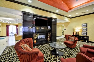 Vestíbulo de hotel con chimenea, dos sillones, una mesita de centro y una alfombra estampada.