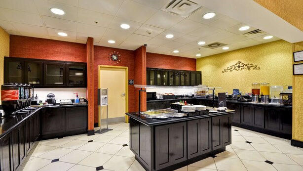 A modern kitchen area with black countertops, a central island, and a clock on the wall.