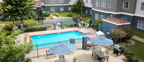 A rooftop pool area with a pool, lounge chairs, and a barbecue grill.