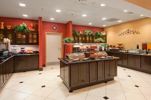 Un área de bufé con diversos alimentos y un reloj en la pared.