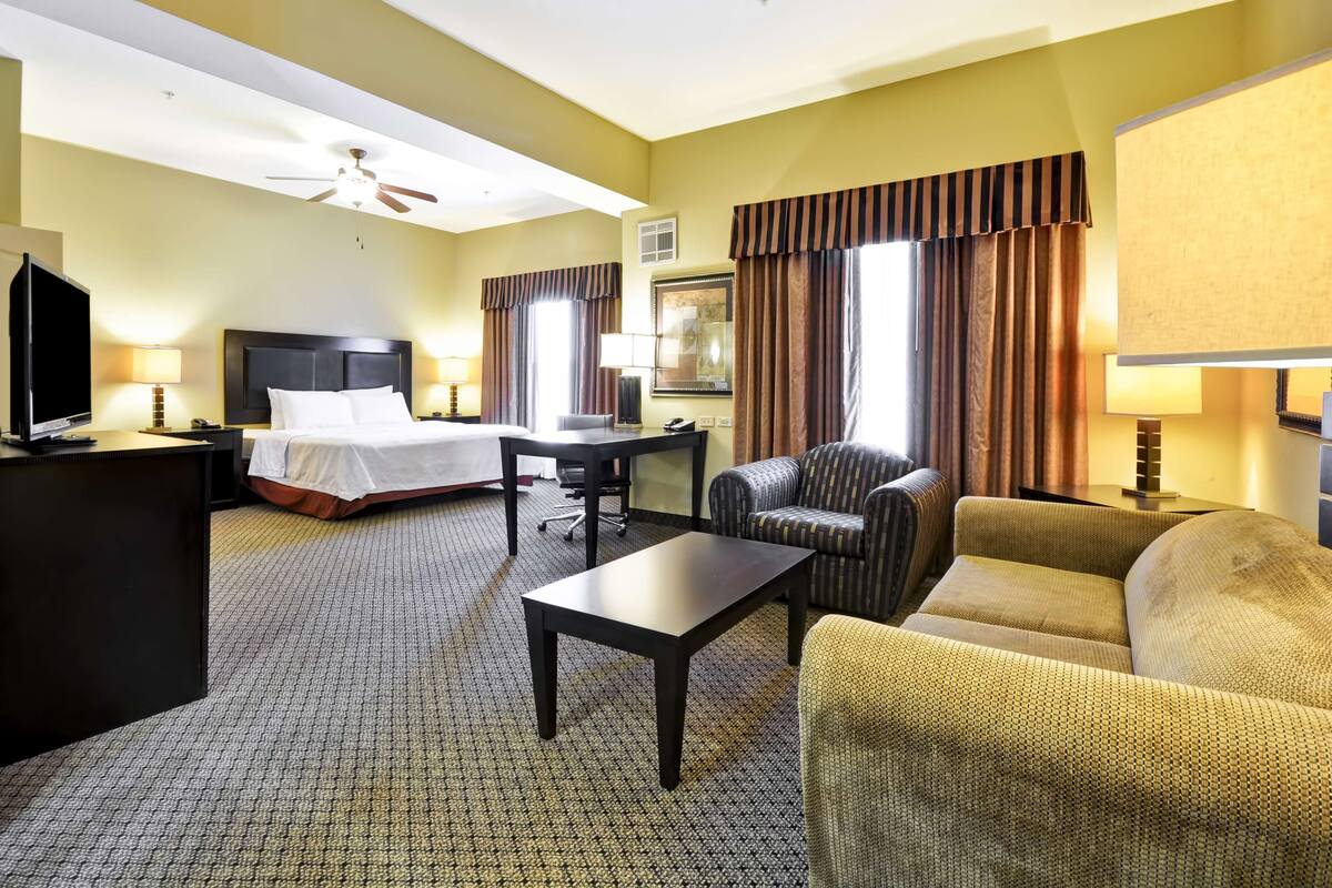 Een hotelkamer met een bed, een bureau, een stoel, een bank en een televisie.