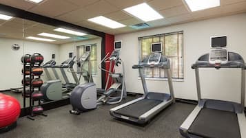 A gym with treadmills, elliptical machines, and a red exercise ball.