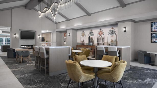 Un moderno vestíbulo de hotel con zona de bar central, espacios para sentarse y decoración en las paredes.