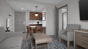 Un espace de vie moderne et compact comprenant un coin cuisine, un coin repas et un coin salon.
