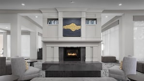 A modern lobby with a fireplace, grey sofas, and a large abstract painting. - Hilton Garden Inn Denver/Highlands Ranch (Littleton)