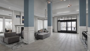 A spacious lobby with a fireplace, seating area, and large windows. - Hilton Garden Inn Denver/Highlands Ranch (Littleton)