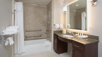 A modern bathroom with a bathtub, shower, vanity with sink, and a large mirror.