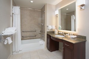 A modern bathroom with a bathtub, shower, vanity with sink, and a large mirror. - Homewood Suites Phoenix Avondale (Avondale)